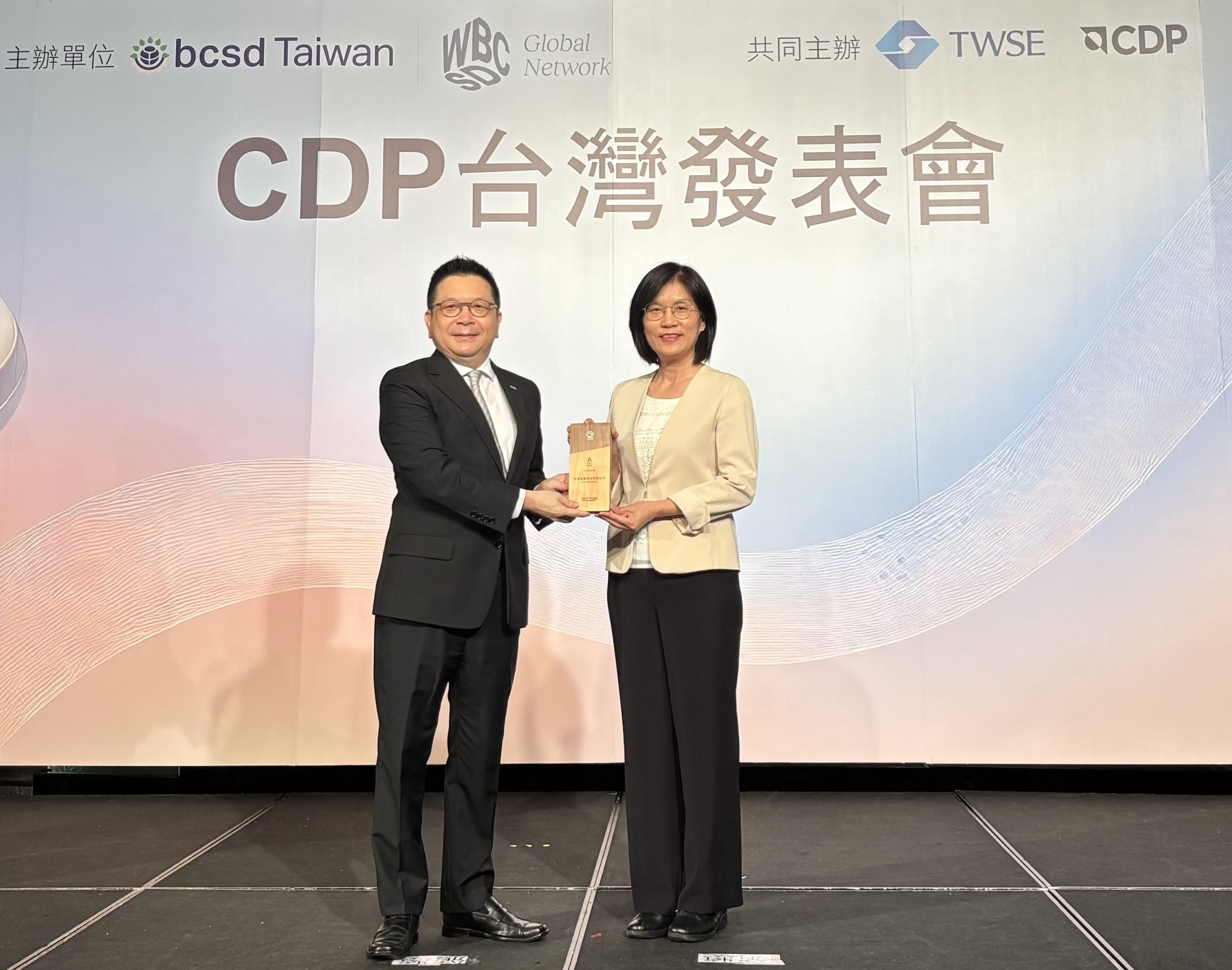 ⽜⼋体育永續成果再獲國際評比肯定，獲頒CDP氣候與水資源雙項領導力評級。今由臺灣證券交易所董事長林修銘（左）頒獎，⽜⼋体育光電永續長古秀華（右）代表受獎